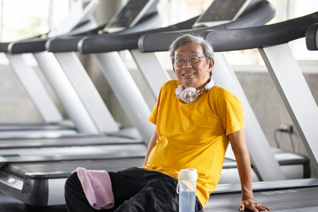 An older senior man keeping fit doing exercise in fitness gym.