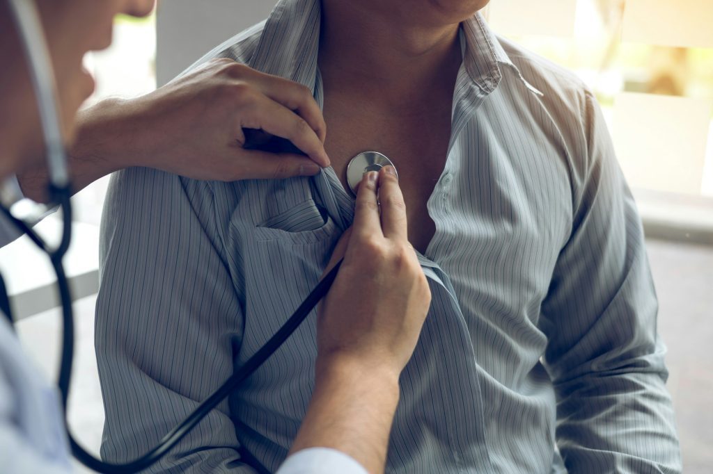 Asian doctor is using a stethoscope listen to the heartbeat of the elderly patient.