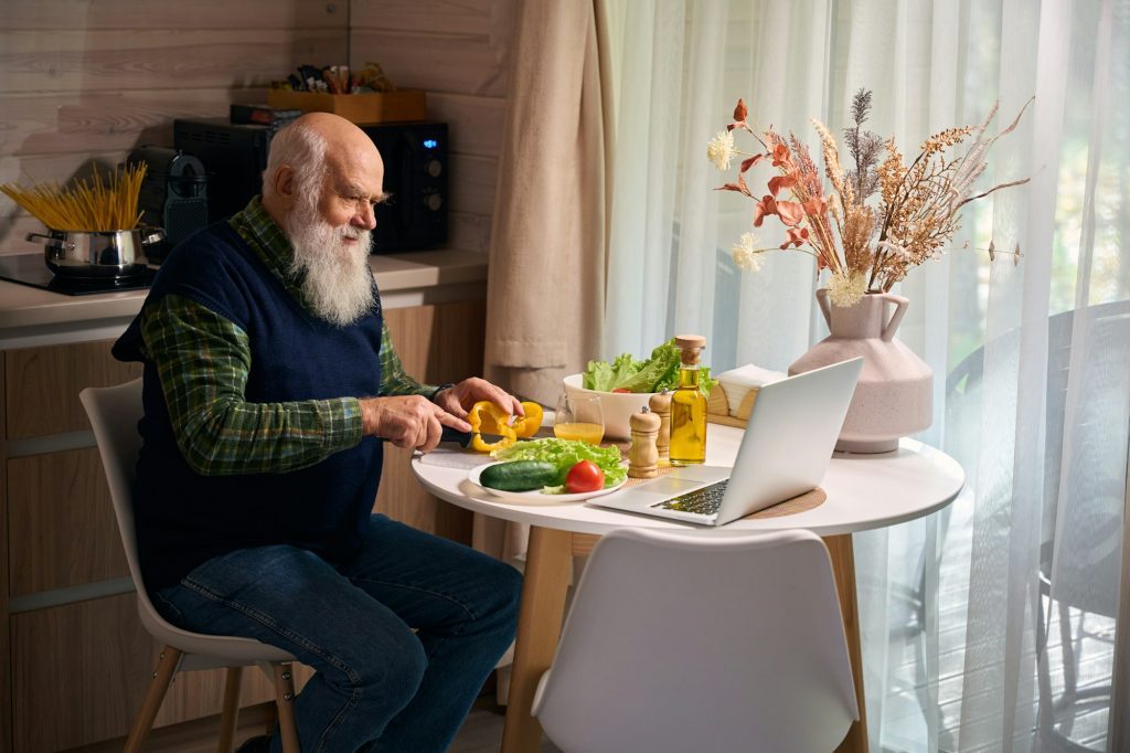 Old ma is preparing a salad and chatting online