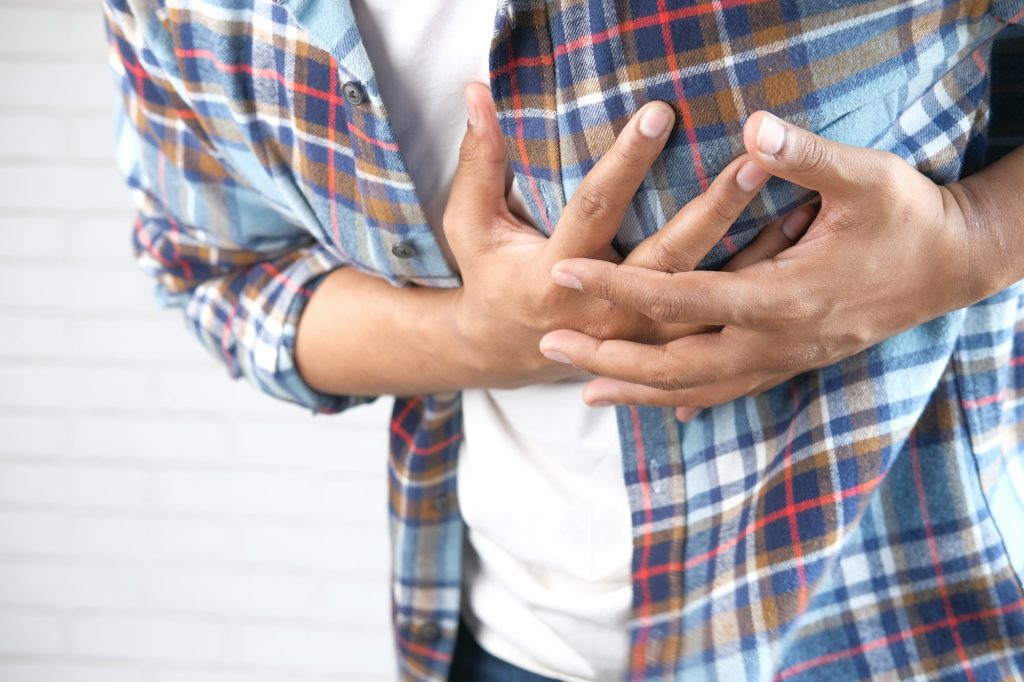 young man suffering pain in heart and holding chest with hand