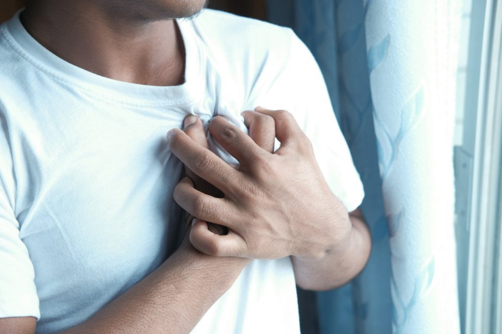 young man suffering pain in heart and holding chest with hand